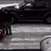 a woman standing in front of a car in the snow