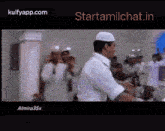 a man in a white shirt is dancing in front of a crowd of people .