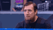 a man with a beard is sitting in front of a sign that says ' just '