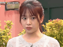 a girl with a ponytail looks at the camera with a sign above her that says ' eas ' on it