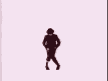 a man in a black suit and hat is dancing on a pink background .