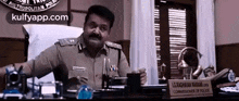 a police officer is sitting at a desk in a room .