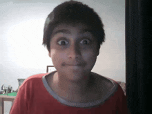 a young boy wearing a red shirt making a funny face