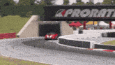 a red race car is going around a curve under a sign that says proram