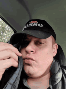 a man wearing a black ellesse hat is making a funny face
