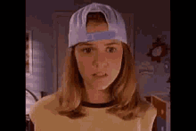 a young girl wearing a baseball cap and a yellow shirt .