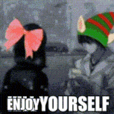 a girl with a pink bow on her head is standing next to a boy wearing an elf hat with the words enjoy yourself below them