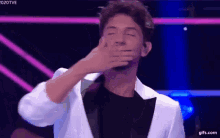 a man in a tuxedo is covering his mouth with his hand ..