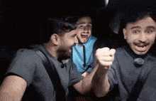 three men are sitting in the back seat of a car with their mouths open