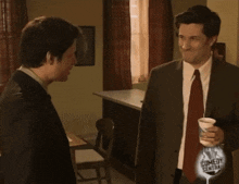 two men are standing in a room with a comedy central logo on the bottom