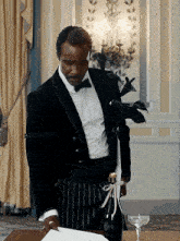 a man in a tuxedo holds a bottle of champagne with a bow on it