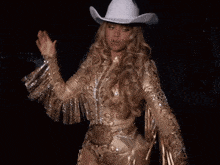 a woman is wearing a gold outfit with fringe on the sleeves and a belt that says ' hollywood ' on it
