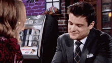 a man in a suit and tie talks to a woman