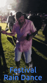 a man in a pink shirt is dancing at a festival
