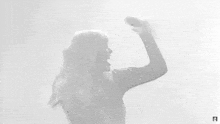 a black and white photo of a woman in a black dress standing in front of a white wall .