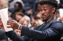 a man in a suit looks at a piece of paper