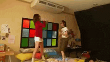 two girls are jumping on a bed in front of a window with stained glass