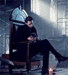 a man is sitting on a throne holding a cat in his lap .