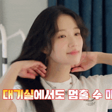 a woman in a white t-shirt with korean writing on it adjusts her hair