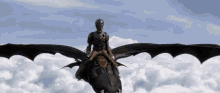a man is riding on the back of a black dragon in the sky