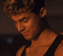 a close up of a man wearing a black tank top and a necklace