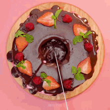 a chocolate cake with strawberries and mint leaves on a cutting board