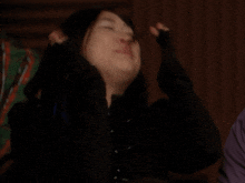 a woman with blue hair is laughing with her hand in her hair