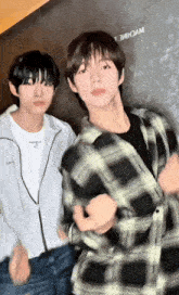 two young men are standing next to each other and one is wearing a plaid shirt