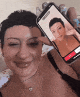 a woman with a tattoo on her neck is holding a cell phone with a picture of another woman on it