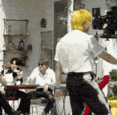 a man with yellow hair is standing in front of a group of people