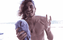 a shirtless man with long hair is holding a towel