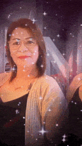 a woman with glasses and a tattoo on her chest is surrounded by sparkly stars