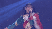 a woman in a colorful jacket is singing into a microphone on a stage