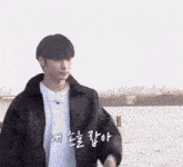 a man in a black jacket is standing in front of a body of water