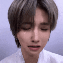 a woman with short hair is crying with her eyes closed and a tear coming out of her eye .