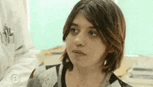 a woman with short hair is making a funny face while looking at the camera .