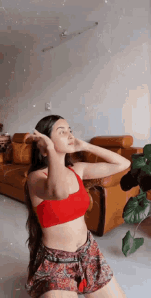 a woman in a red top and shorts is sitting on the floor in front of a couch .