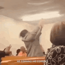 a man is dancing in a church with his arms in the air while a woman watches .