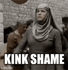 a woman in a hijab is standing in front of a stone wall with the words `` kink shame '' written on it .