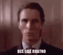 a man in a suit and tie says " все еще платно " in a foreign language