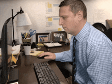 a man sits at a desk using a computer keyboard
