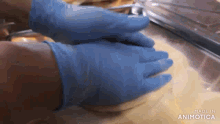 a person wearing blue gloves is holding a piece of food .