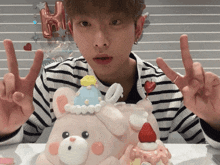 a man giving a peace sign in front of a cake with a teddy bear on top