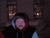 a man with a beard is wearing a hoodie in front of a sign that says " pants "