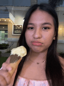 a woman is holding an ice cream cone in her hand and making a funny face