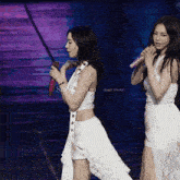two women holding microphones on a stage with the words snow drop aespa winter on the bottom right