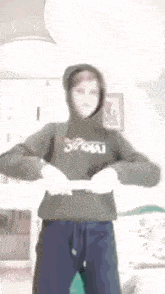 a young boy wearing a hoodie is standing in a room .