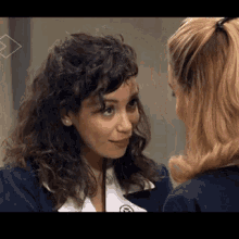 two women are looking at each other and one has a badge on her jacket that says ' a ' on it