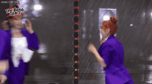 a group of girls in purple suits are standing next to each other with the words " the bomb dance " on the bottom right
