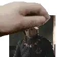 a hand is holding a man 's head in front of a picture of a man in a helmet .